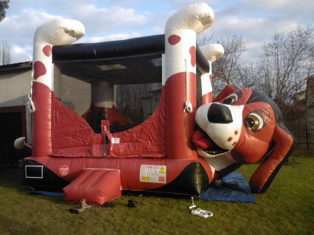 Dmuchańiec w kształcie psa rasy beagle z wystawionym językiem i czerwonymi elementami na trawniku.